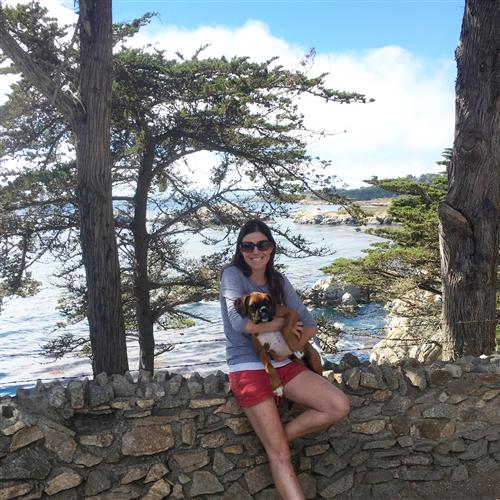 A woman sitting on a stone wall holding a puppy